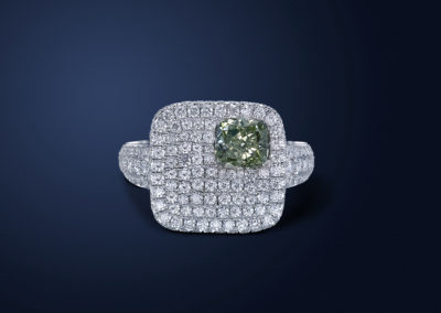 Handmade 18k white gold ring. The cushion cut natural yellow green diamond is set in a creative way to accentuate its uniqueness. The ring is crusted with pure white round diamonds.